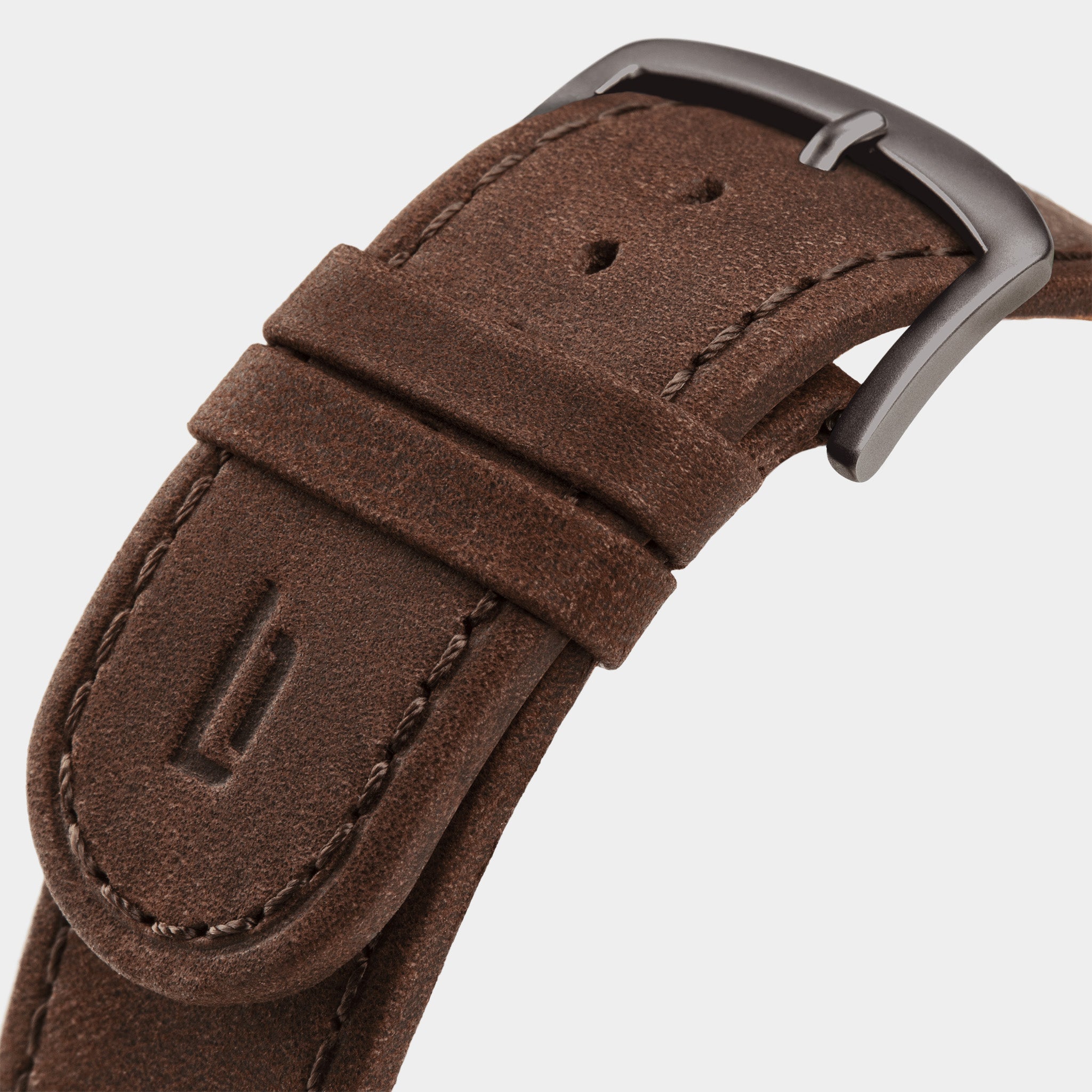 Close-up of brown leather watch strap with metal buckle and stitched detailing