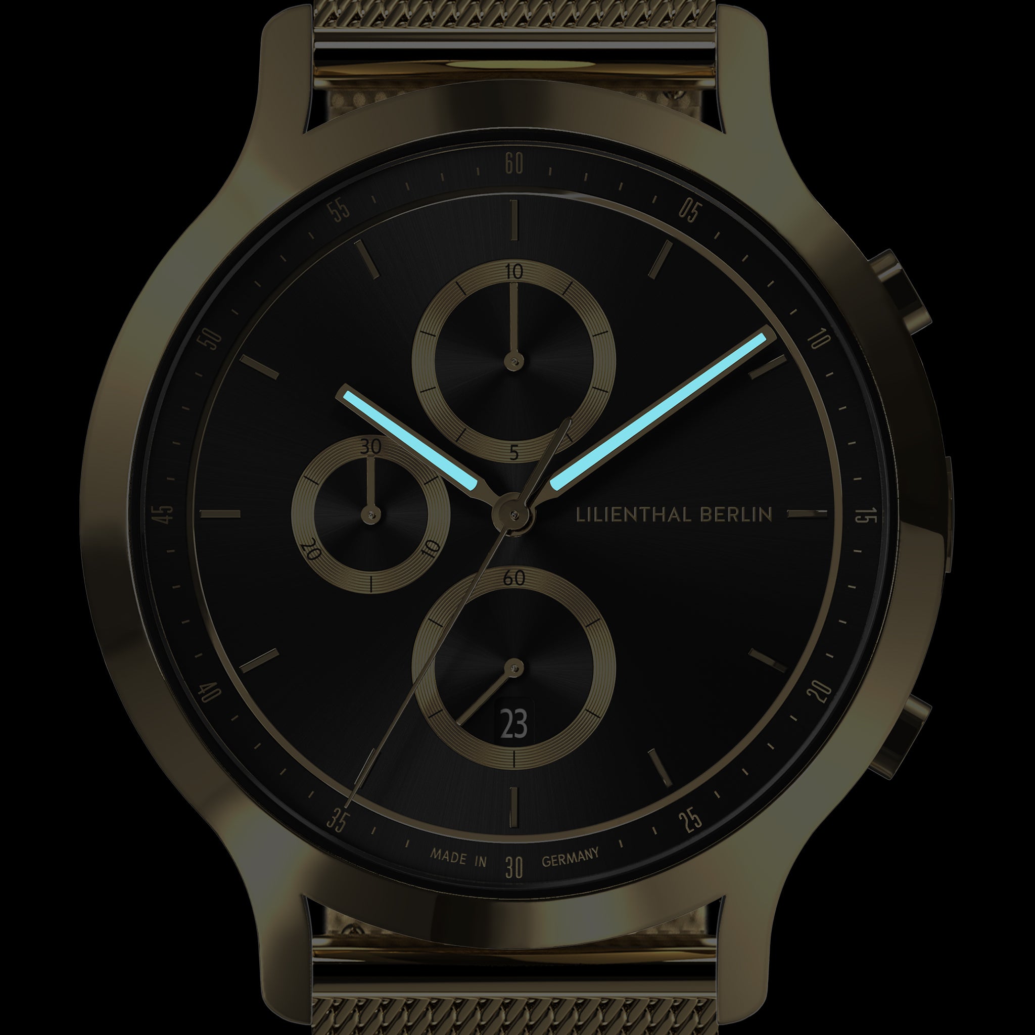 Close-up of a black chronograph watch with gold accents, mesh strap, and luminous hands.