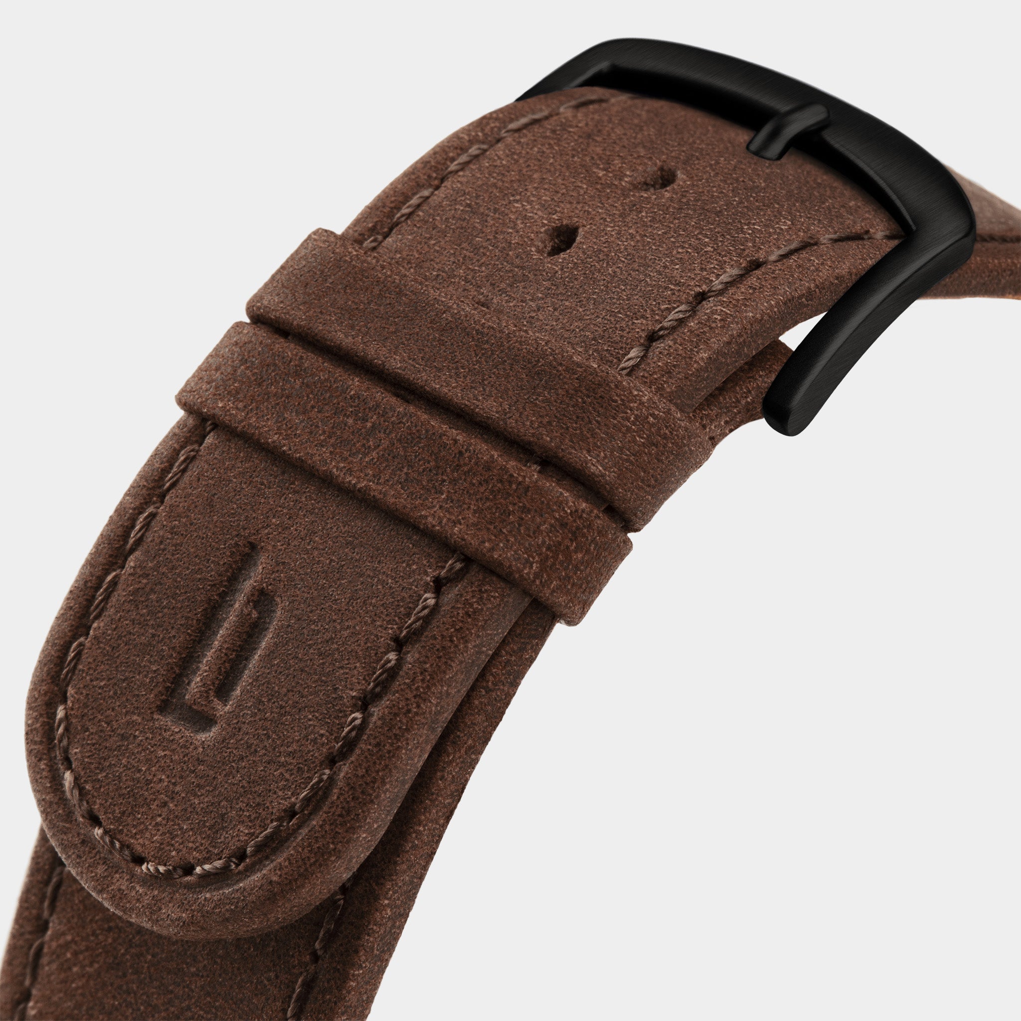 Brown leather watch strap with black buckle and stitched detailing on light background