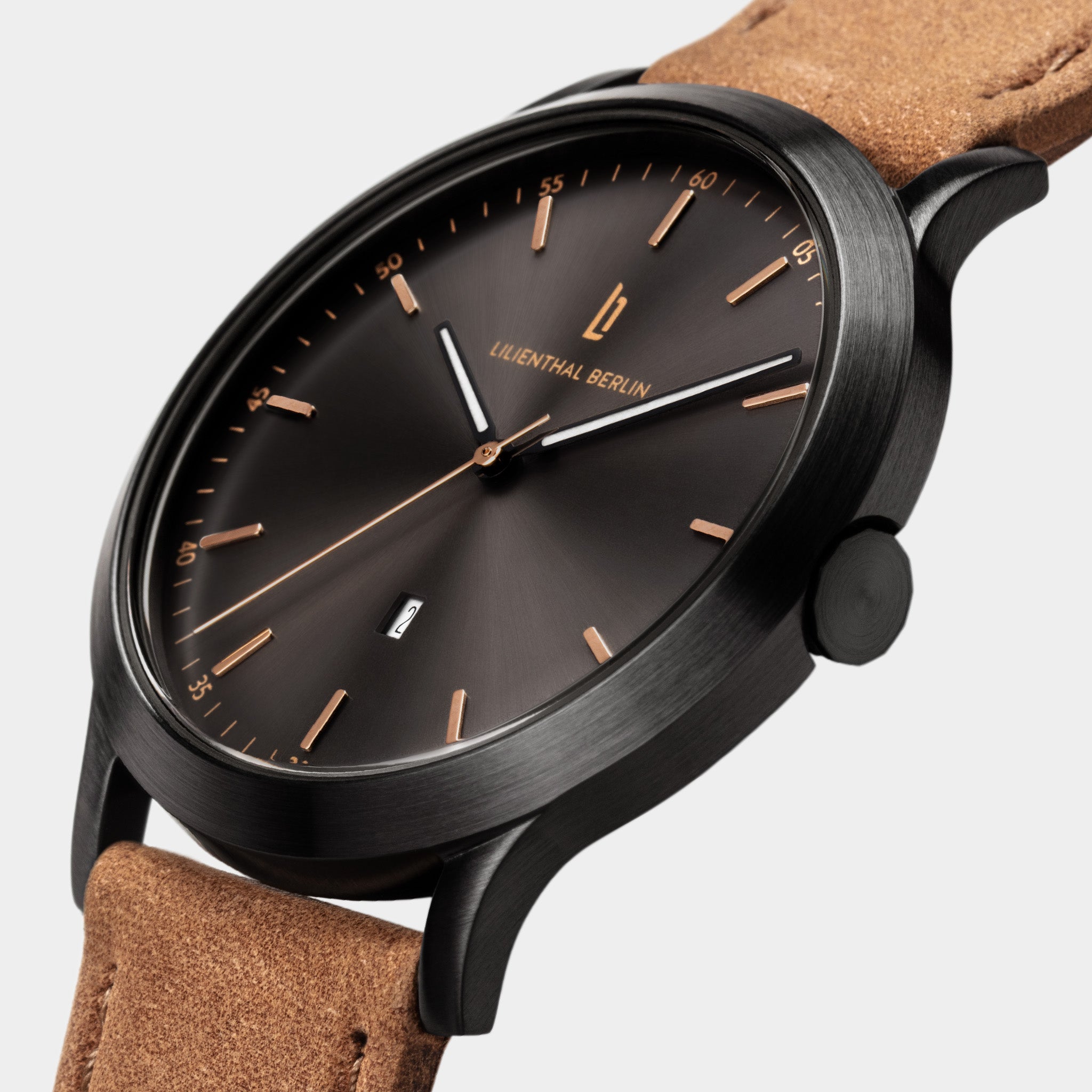 Minimalist black watch with brown dial, gold markers, date display, and tan suede strap
