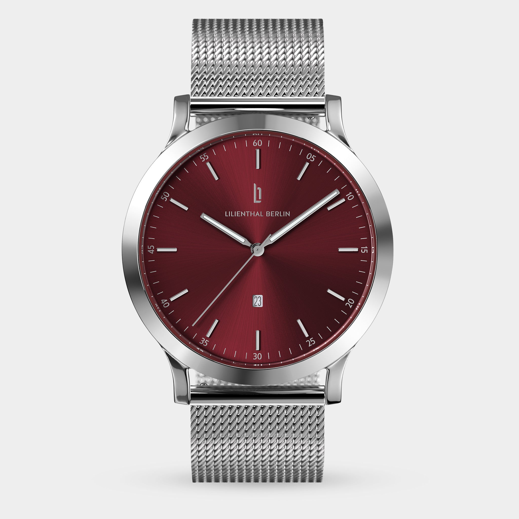 Silver mesh band watch with a red dial and minimalist markers on a neutral background