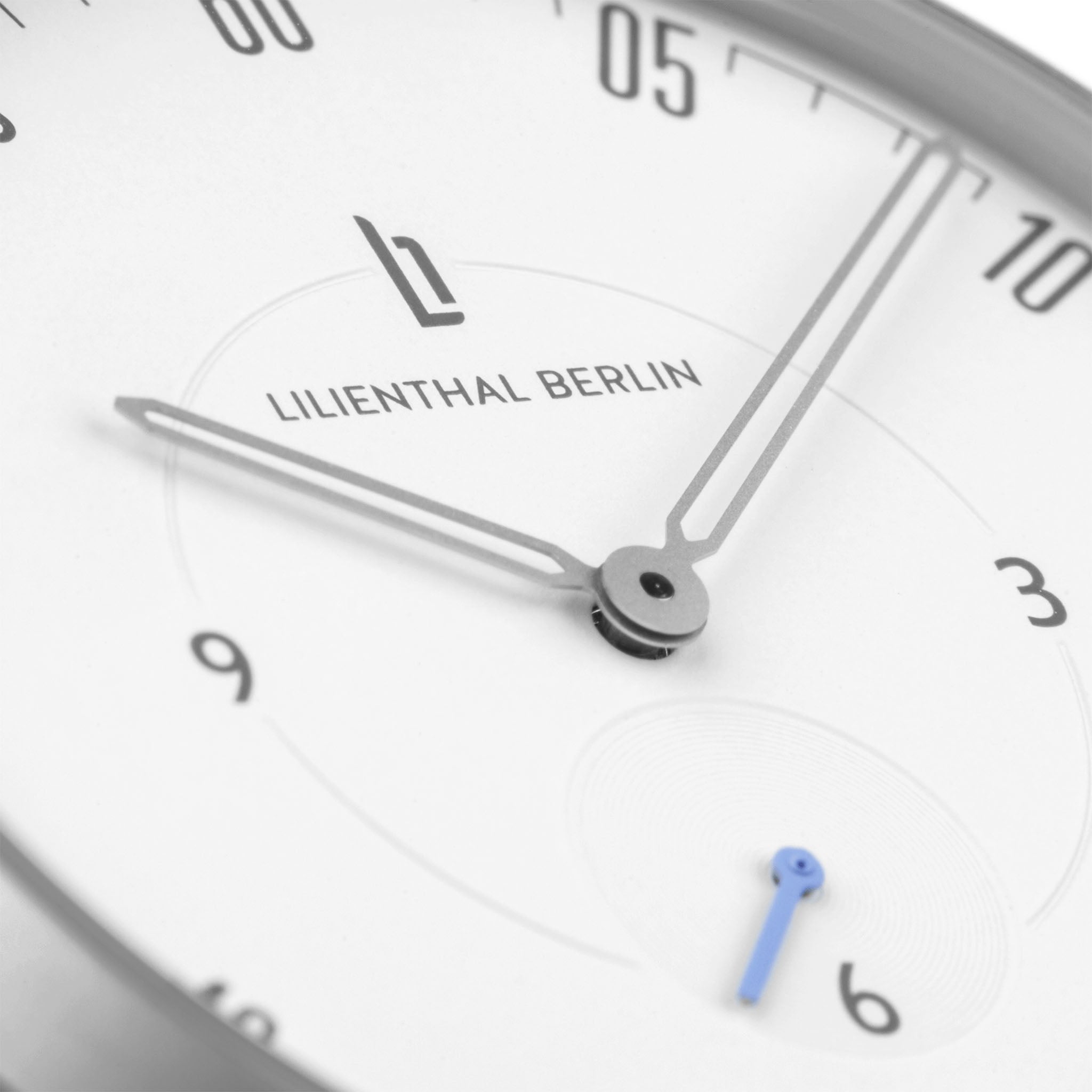 Minimalist analog watch face with silver hands, white dial, and subtle blue subdial hand