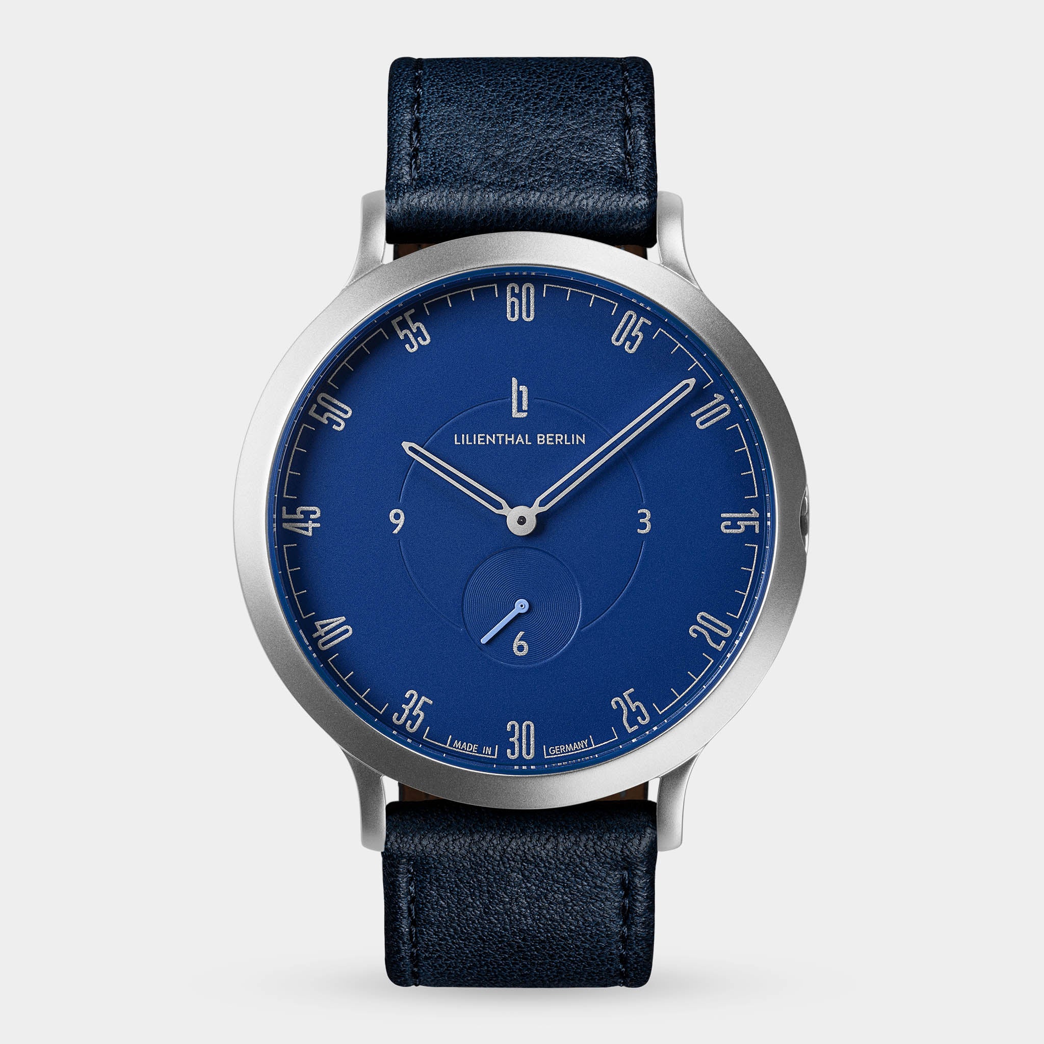 Minimalist blue dial wristwatch with silver case and black leather strap on light background