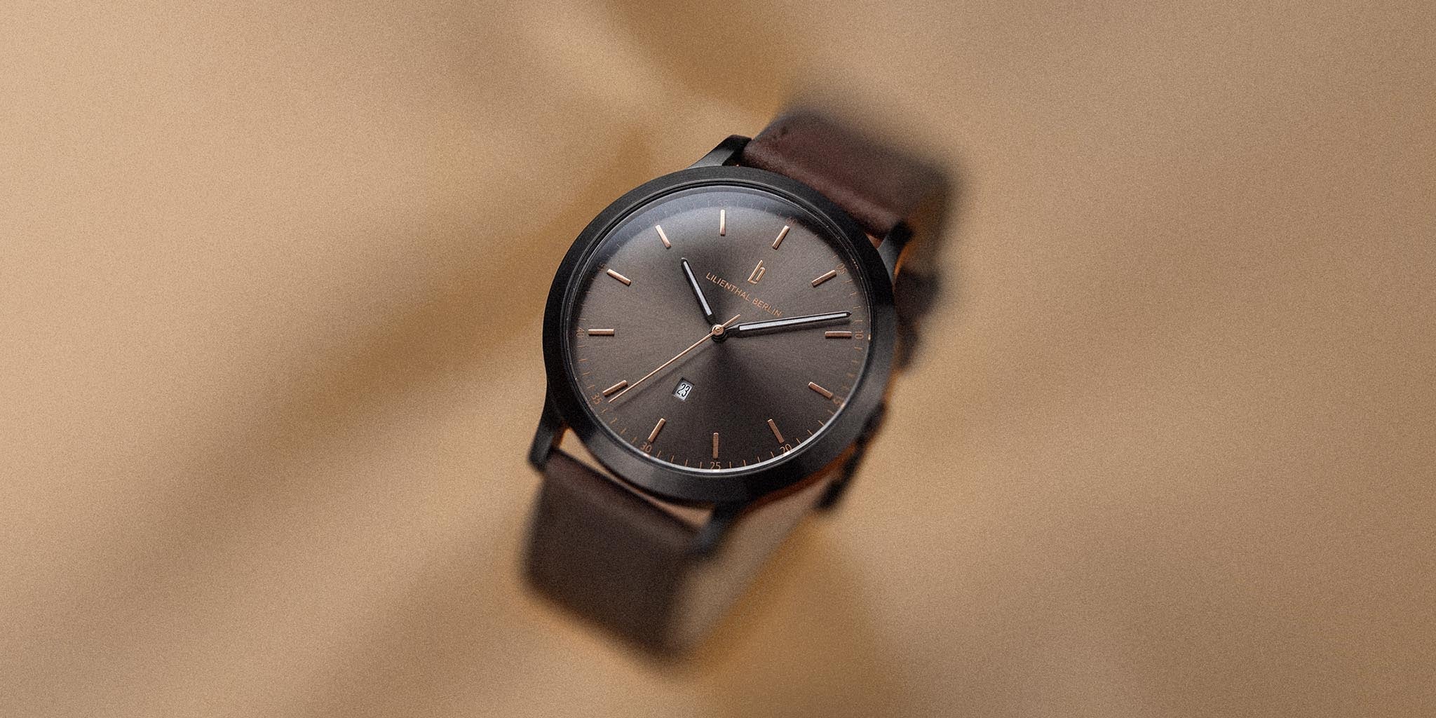 Minimalist brown wristwatch with black case and brown leather strap on beige background