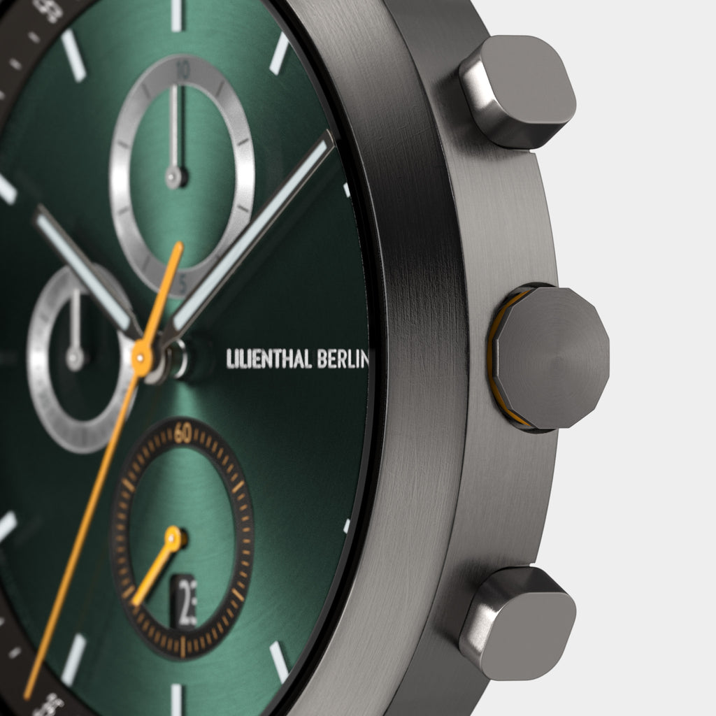 Close-up of a green chronograph watch face with metallic case and orange second hand