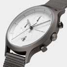 Minimalist chronograph watch with white dial, subdials, and mesh stainless steel strap