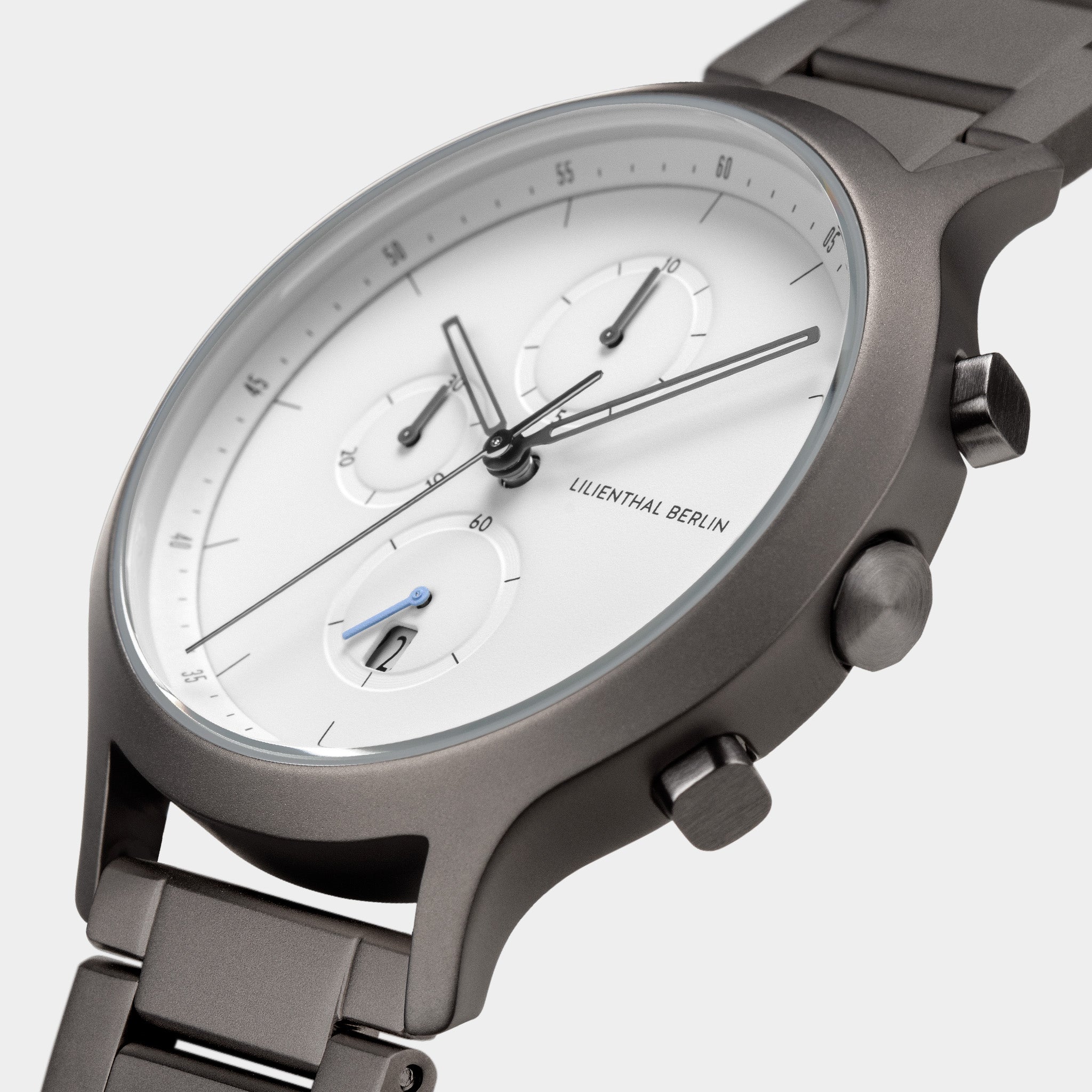 Minimalist chronograph watch with white dial and metal strap, subdials, and date display.