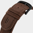 Close-up of brown leather watch strap with black buckle and detailed stitching