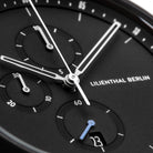 Close-up of a modern black chronograph watch face with subdials and date display.