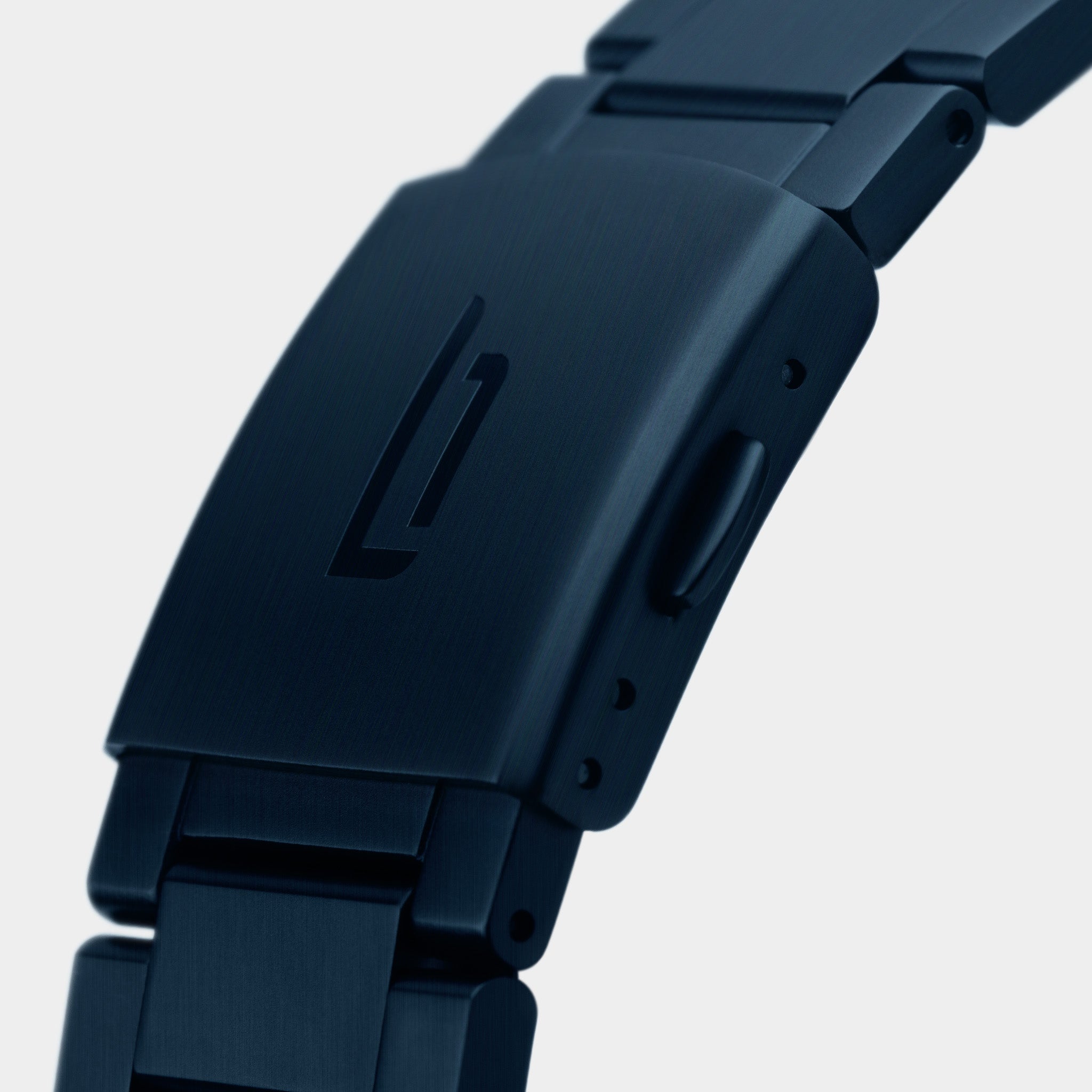 Close-up of a matte black metal watch clasp with engraved logo on a linked bracelet