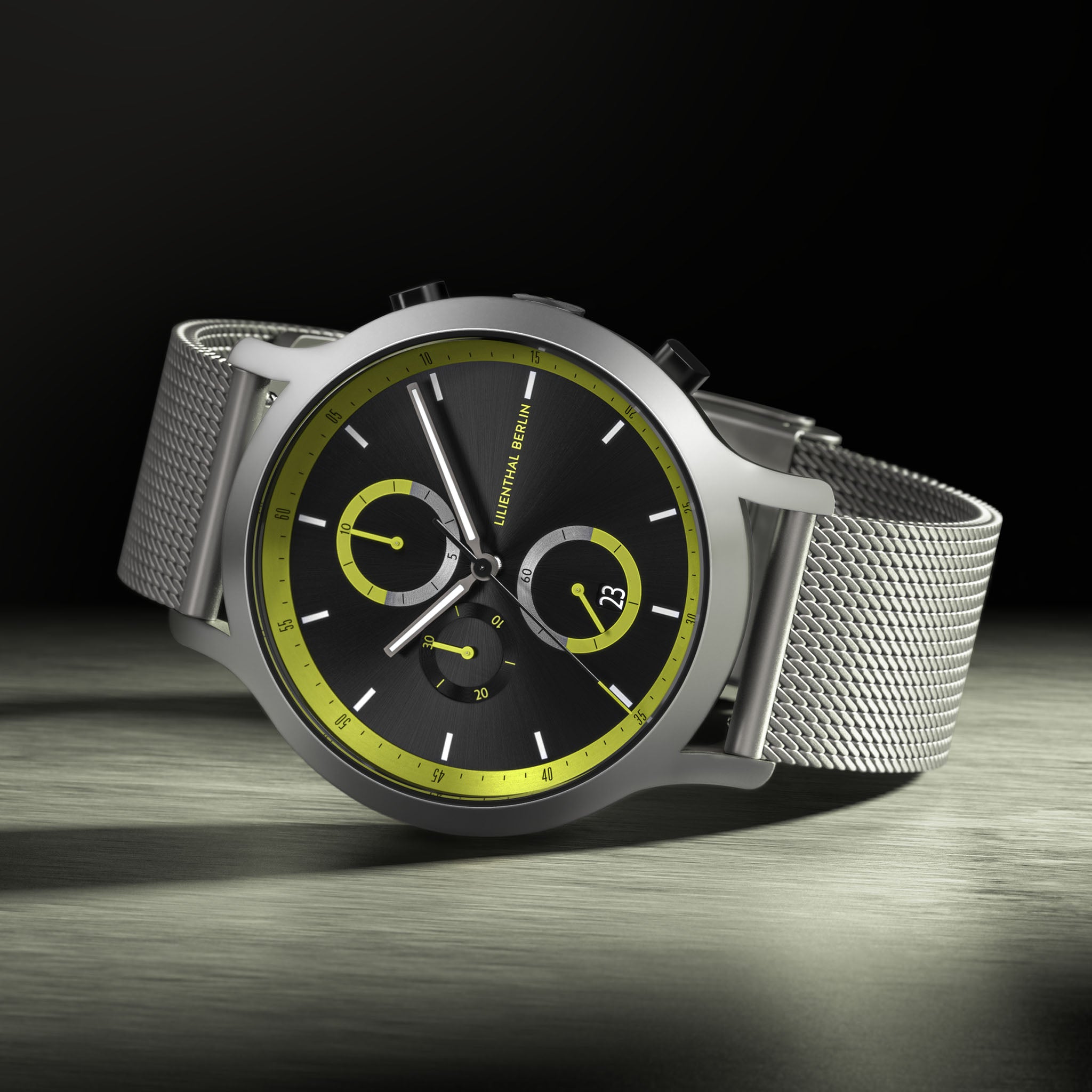 Modern chronograph watch with black and yellow dial, silver mesh strap, and bold accents