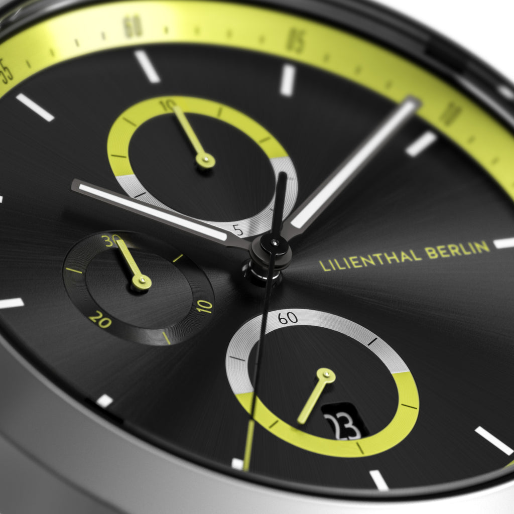 Close-up of modern black watch face with yellow accents, subdials, and date display