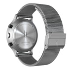 Stainless steel chronograph watch with mesh band viewed from the back, showing engraved case details.
