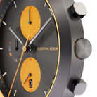 Close-up of a modern black watch with orange subdials, chronograph functions, and date display