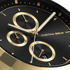 Close-up of a black and gold chronograph watch face with subdials and date display