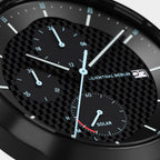Close-up of a black chronograph watch with carbon fiber dial and luminous blue hands