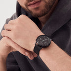 Man wearing a modern black mesh strap wristwatch with minimalist dial design