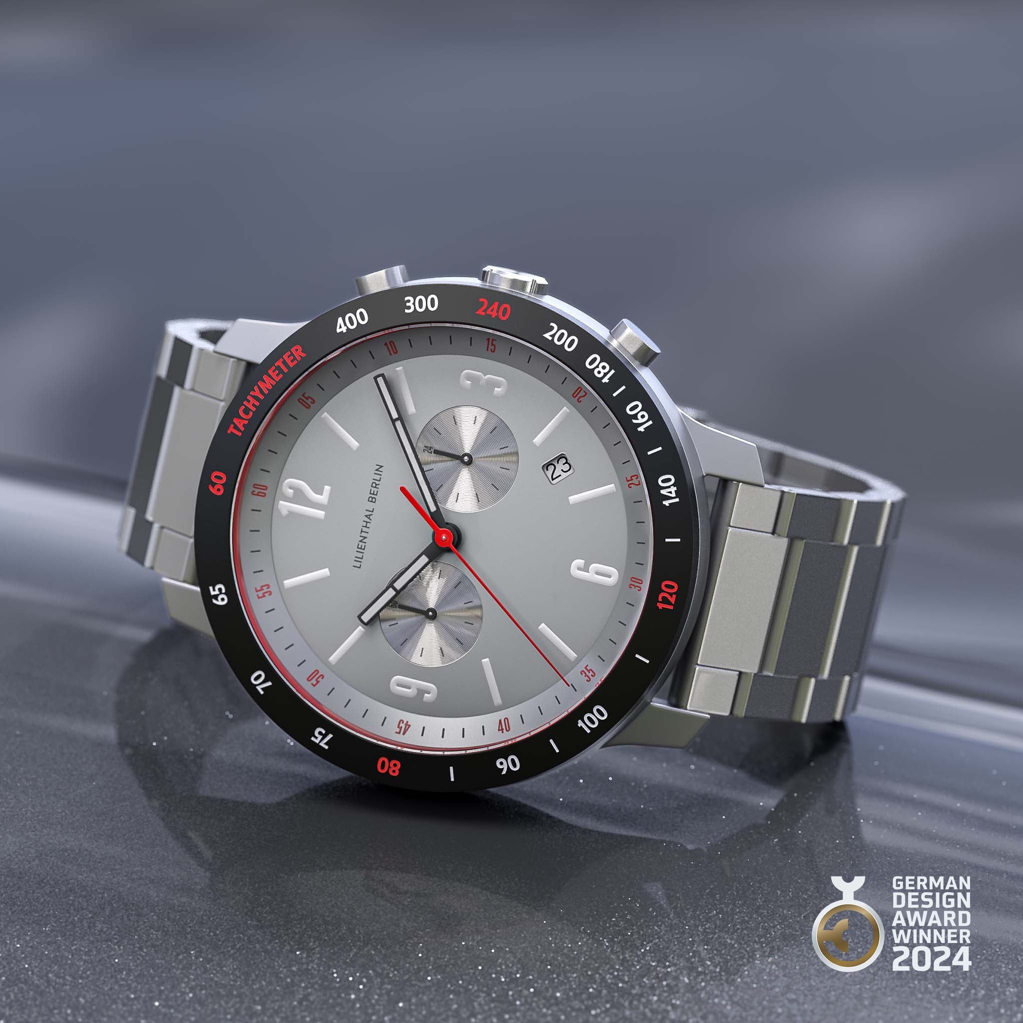 Silver chronograph watch with tachymeter bezel, metal strap, and German Design Award 2024 badge.