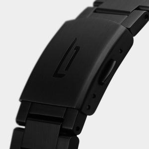 Close-up of a matte black stainless steel watch clasp with engraved logo on bracelet