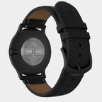 Back view of a black stainless steel watch with leather strap and engraved caseback
