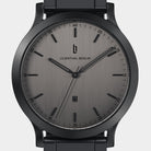 Minimalist black wristwatch with brushed gray dial, date window, and black metal strap