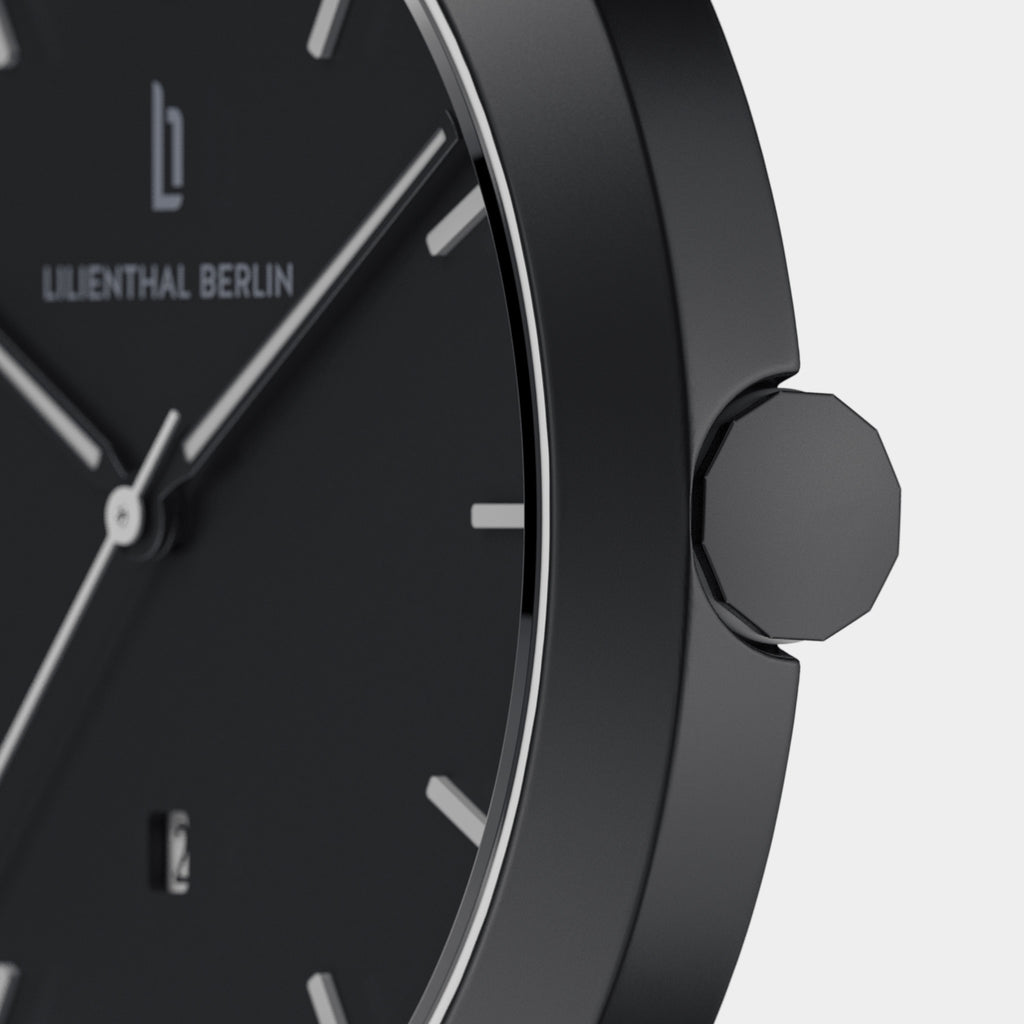 Close-up of minimalist black wristwatch with date display and silver hands.