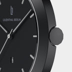 Close-up of minimalist black wristwatch with date display and silver hands.