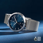 Minimalist silver mesh wristwatch with blue dial, date display, and German Design Award badge.