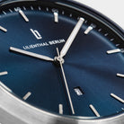 Close-up of a modern watch with a blue sunray dial, silver hands, and date display