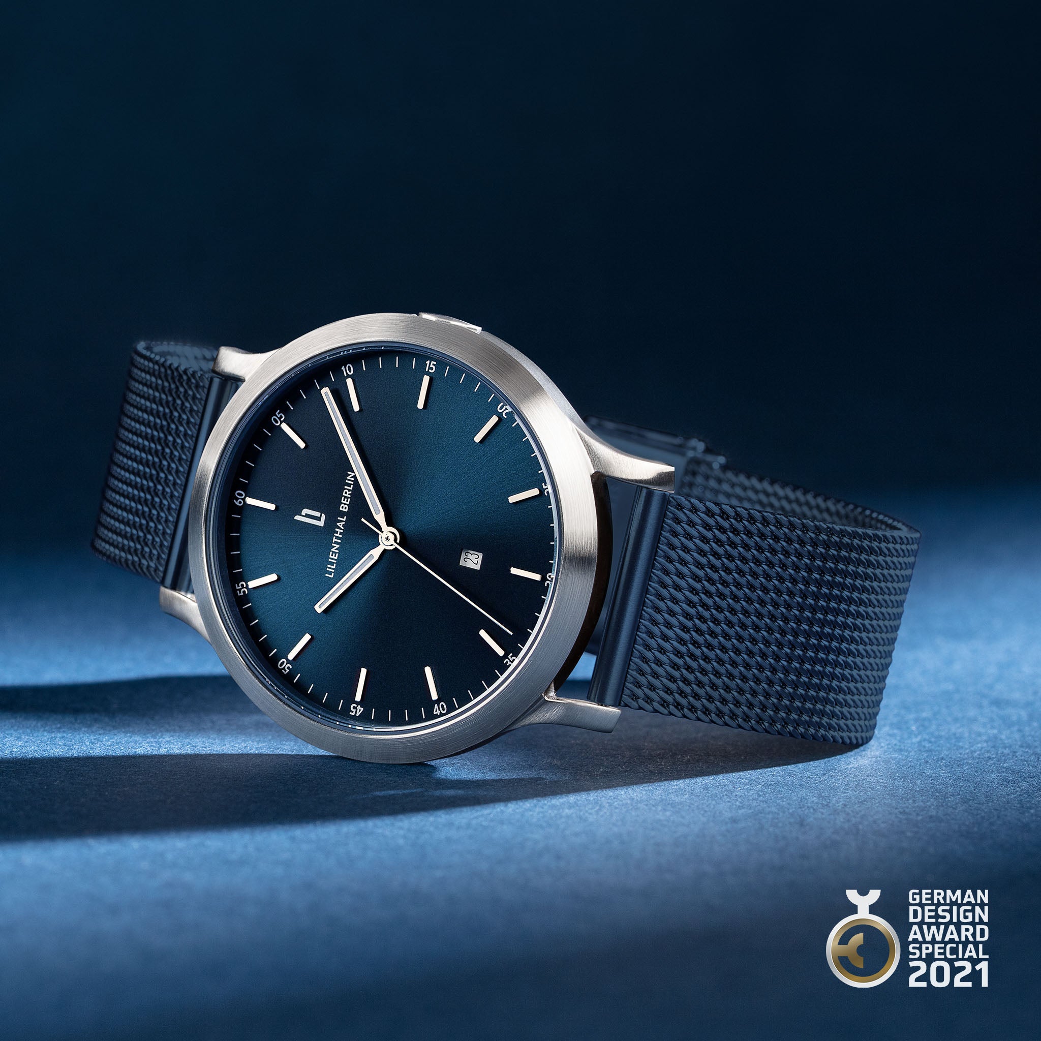 Minimalist blue dial wristwatch with mesh strap, stainless steel case, award badge, modern design