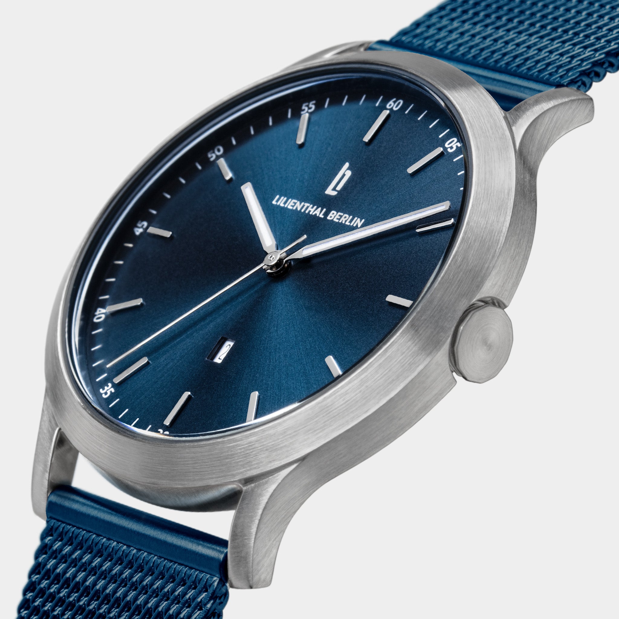 Minimalist blue dial wristwatch with silver case and blue mesh strap, close-up view