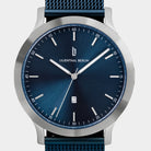 Minimalist blue dial watch with silver case, mesh strap, and date display