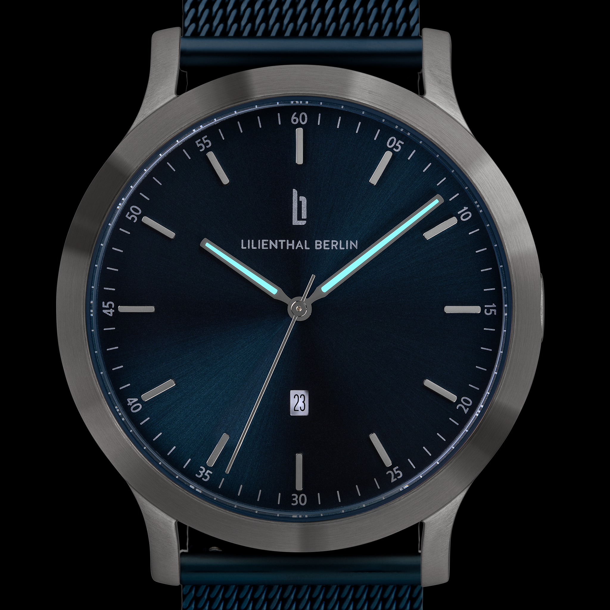 Minimalist blue dial watch with silver case, mesh strap, and luminous hands