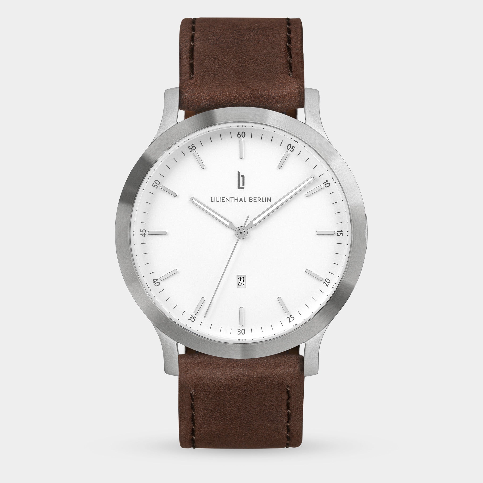 Minimalist silver wristwatch with white dial and brown leather strap on light background