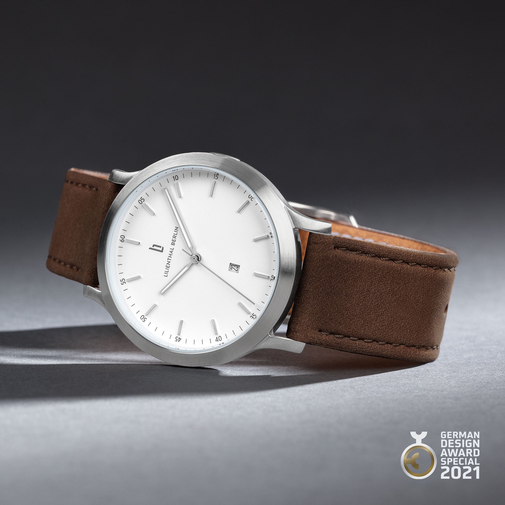 Minimalist silver watch with white dial, date display, brown leather strap, German Design Award 2021.