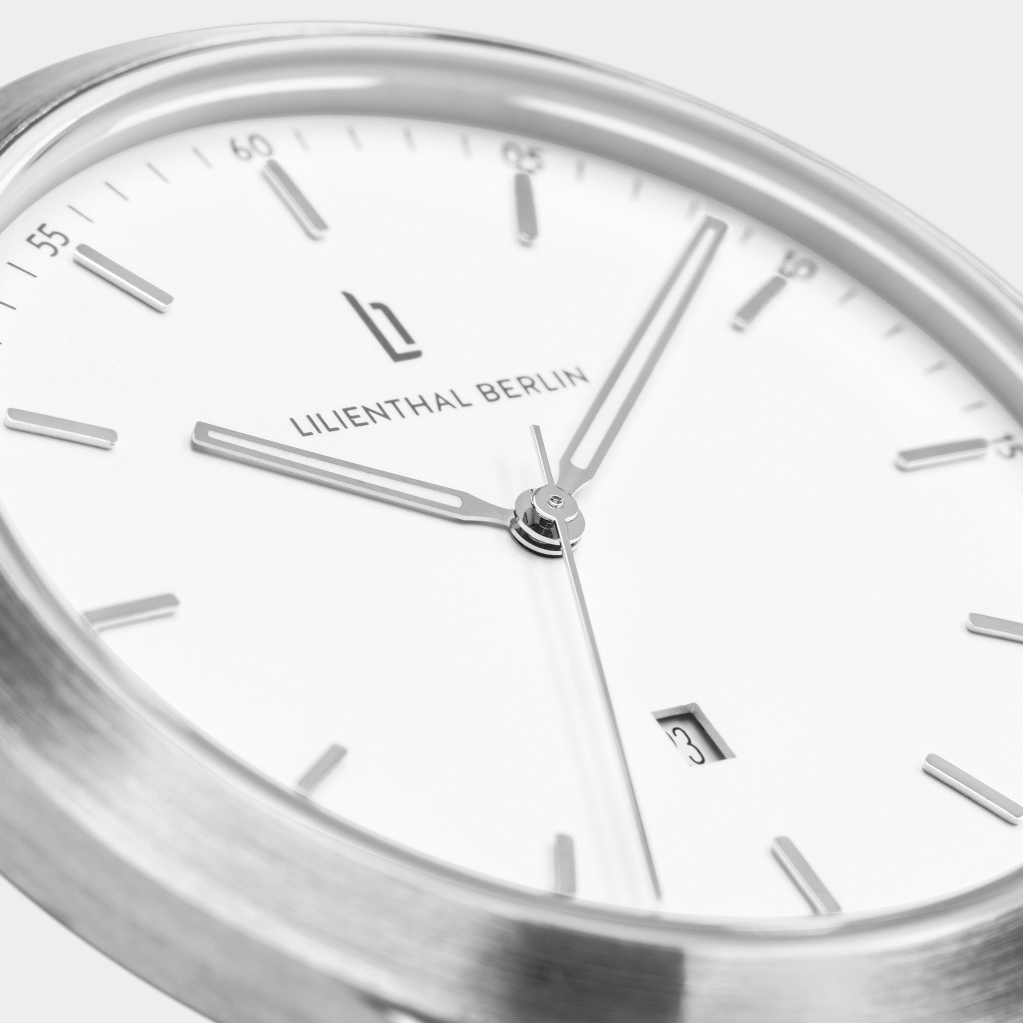Close-up of modern minimalist watch face with silver hands and date display