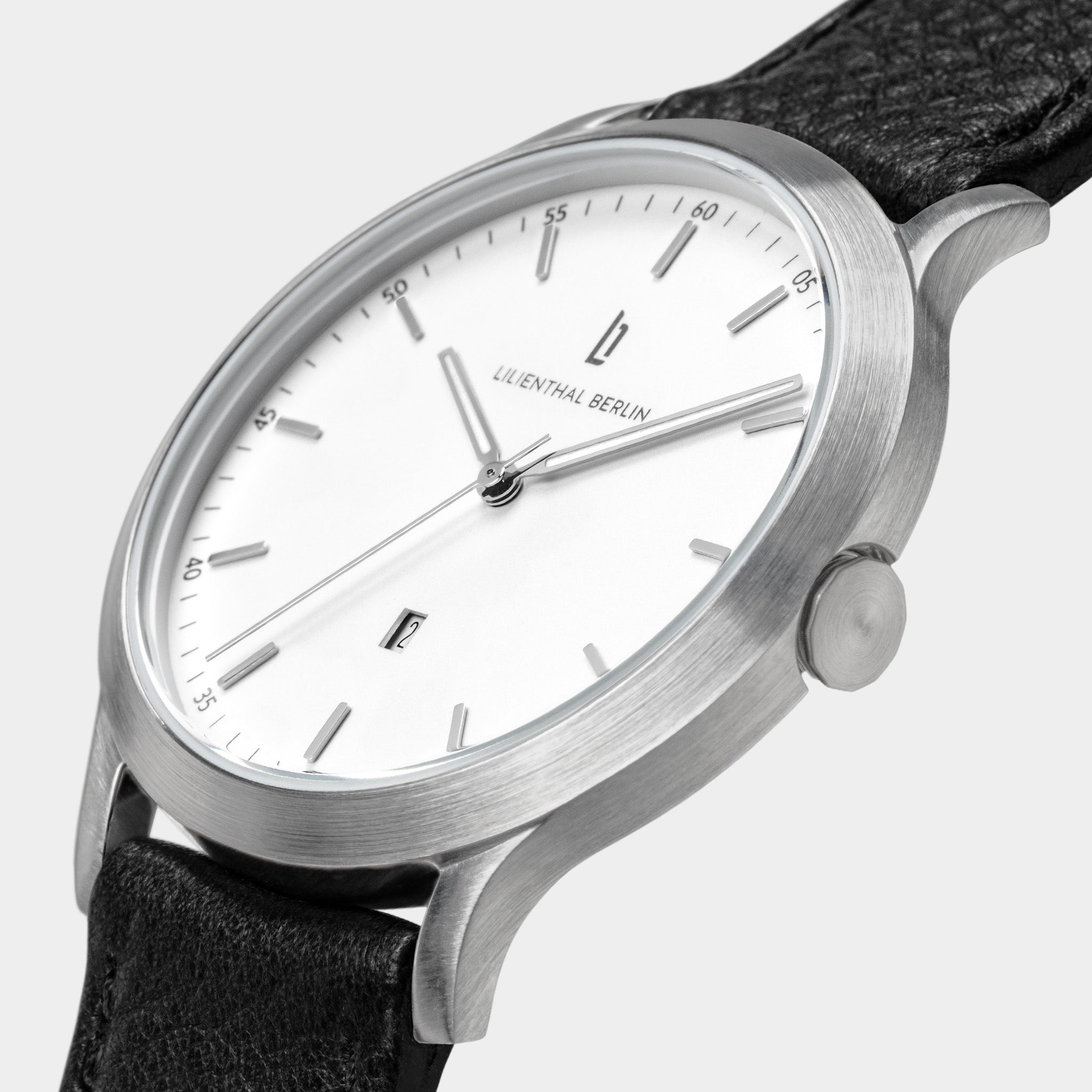 Minimalist silver wristwatch with white dial, black leather strap, and date display