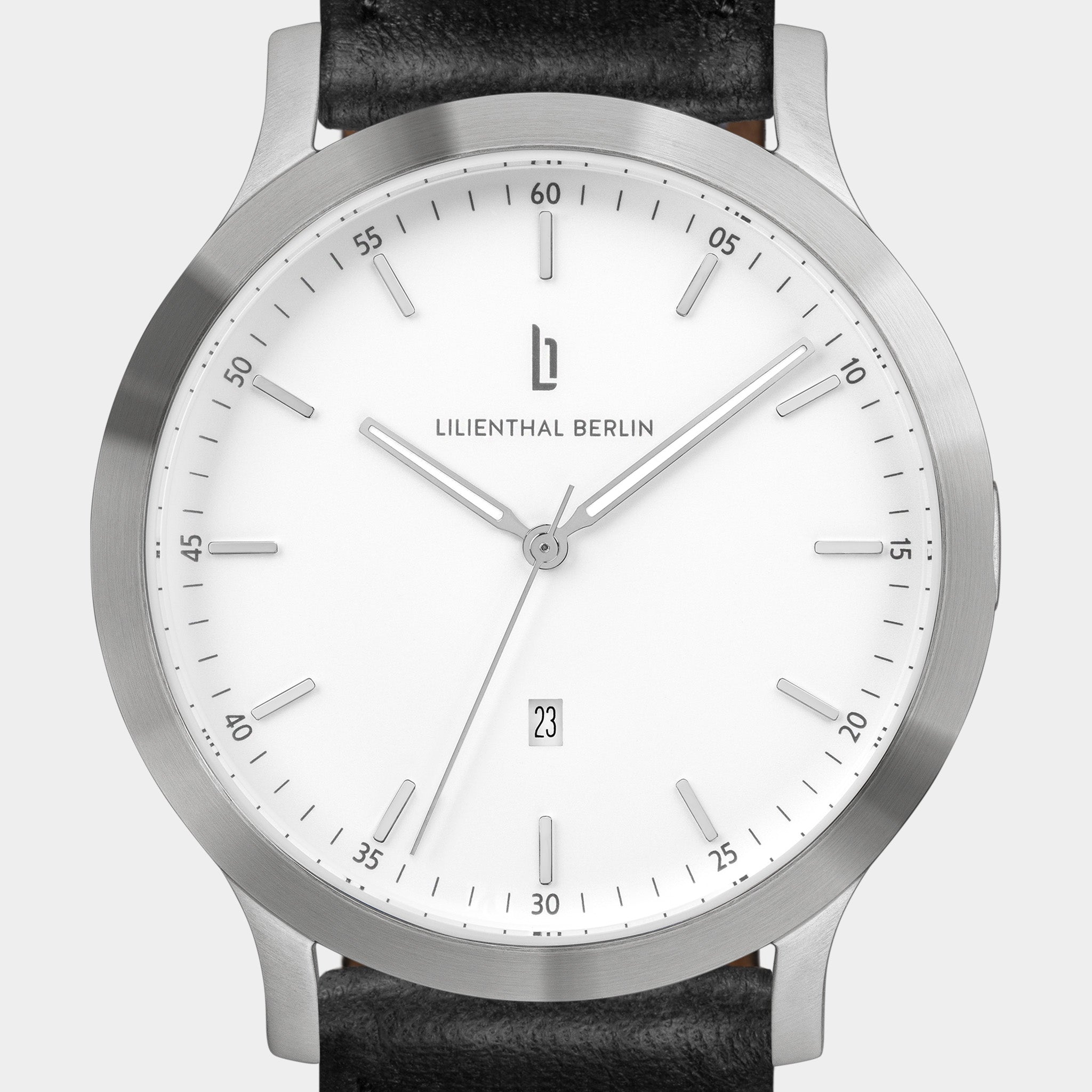 Minimalist silver watch with white dial, date display, and black leather strap