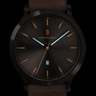 Modern black analog wristwatch with brown strap, gold markers, luminous hands, and date display