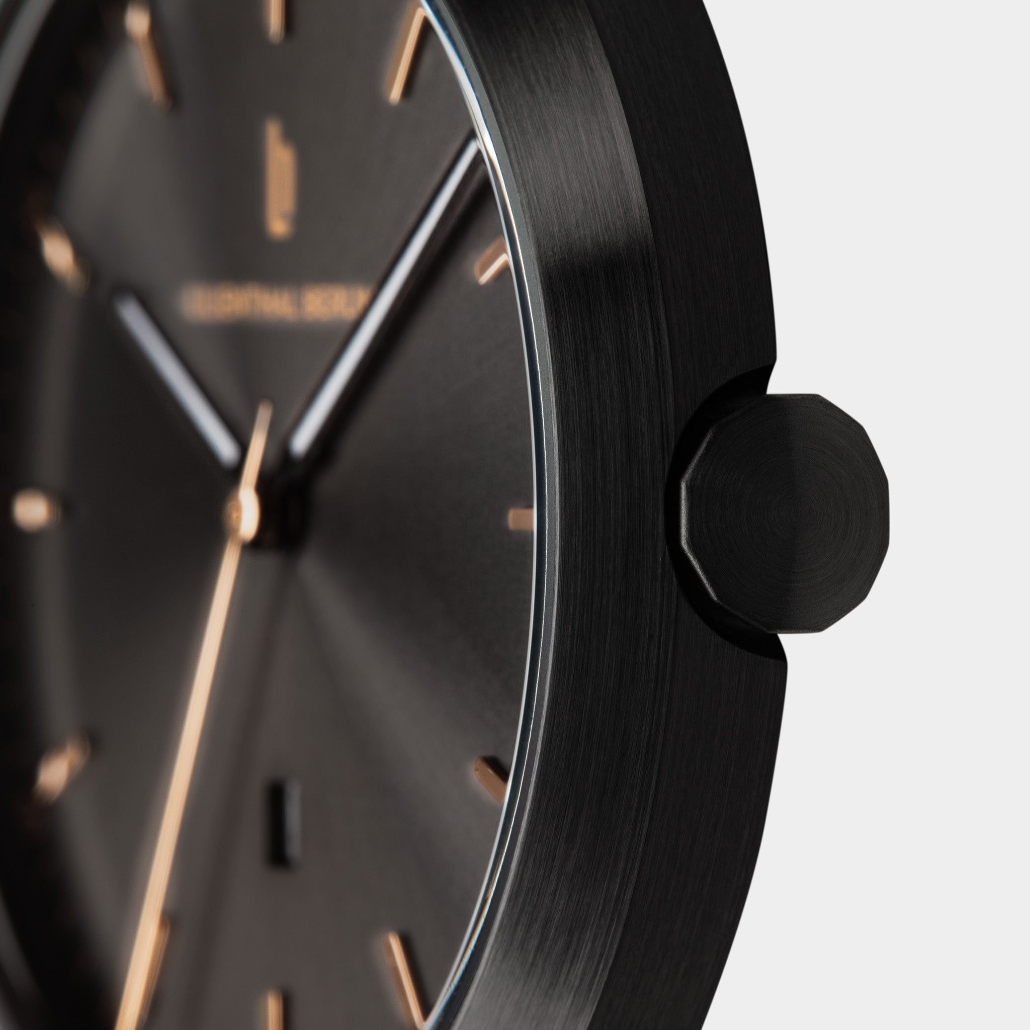 Close-up of a minimalist black wristwatch with gold markers and brushed metal casing.