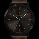 Minimalist black wristwatch with bronze mesh strap, luminous hands, and date display
