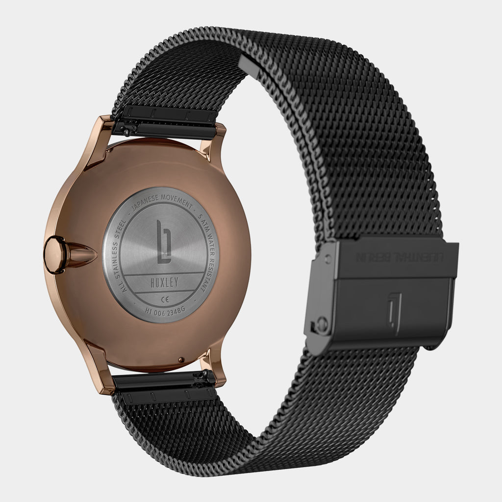 Back view of a rose gold watch case with stainless steel mesh black strap and engraved details
