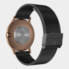 Back view of a rose gold watch case with stainless steel mesh black strap and engraved details