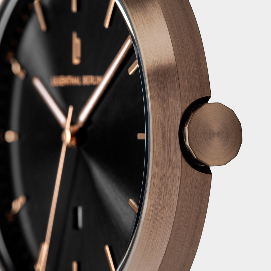 Close-up of a modern wristwatch with black dial and rose gold case and markers