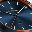 Close-up of a modern blue watch face with orange accents and date display
