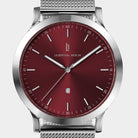 Silver mesh strap watch with a red sunburst dial, minimalist markers, and date display