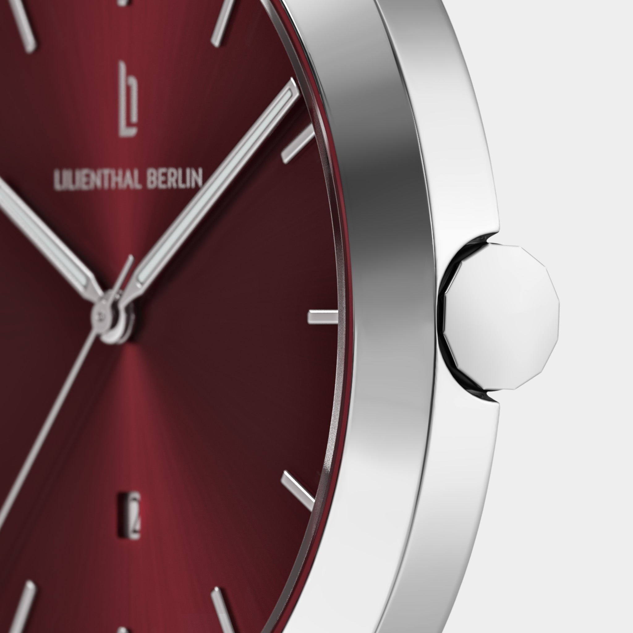 Close-up of a minimalist wristwatch with red dial, silver hands, and stainless steel case