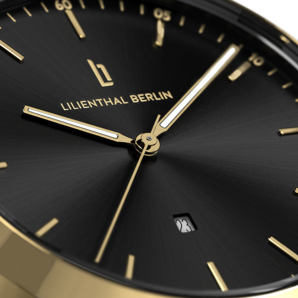 Close-up of black and gold watch face with date display and minimalist design