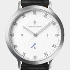 Minimalist silver wristwatch with white dial, black leather strap, and small blue seconds hand
