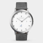 Minimalist silver wristwatch with white dial, black leather strap, and numbered minute markers.